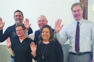 five people waving at the camera