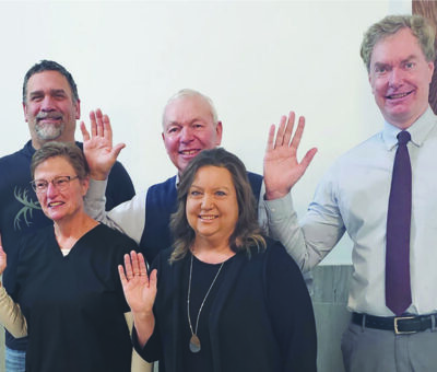 five people waving at the camera