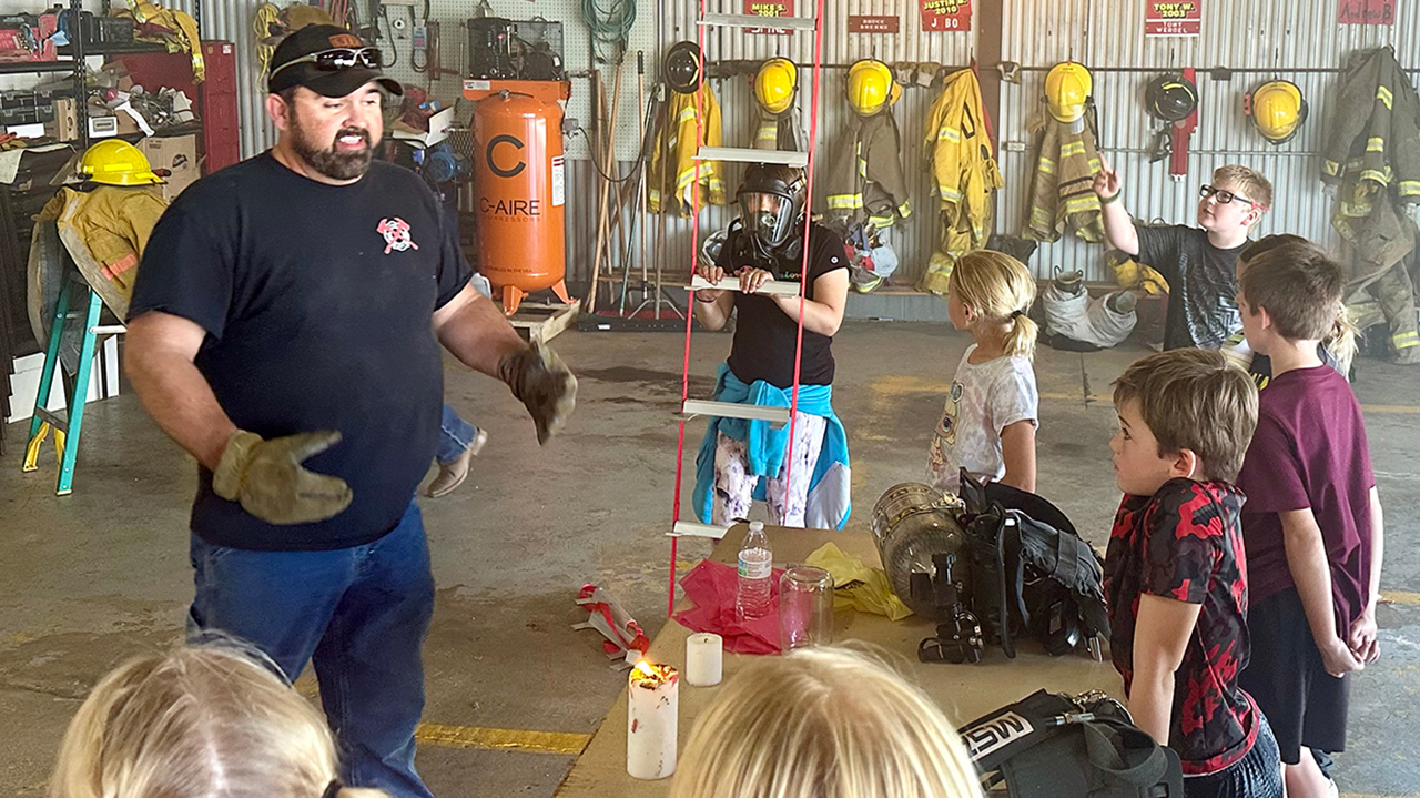 firefighter speaking to children in fire hall