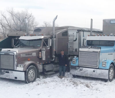 three men standing with semi trucks