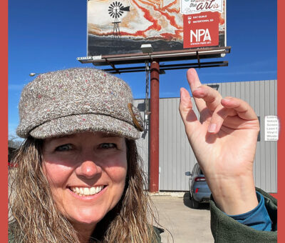 Kay Quale pointing to a billboard behind her