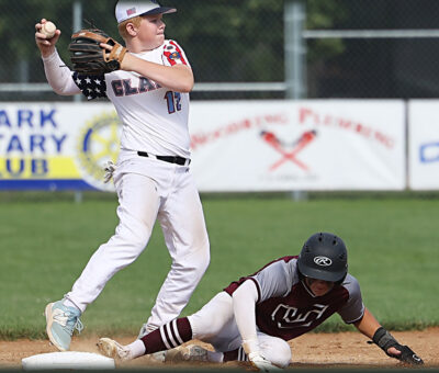 young teenage baseball player throwing a ball after getting the player at his feet out