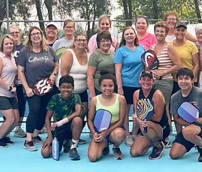 several people posed together on a pickleball court