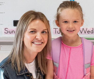 adult woman in denim jacket with young girl wearing purple backpack and pink tee shirt