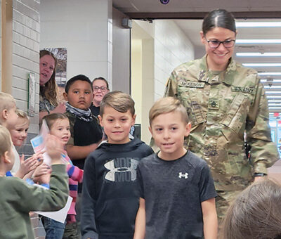 amber nickeson in uniform walking behind two students