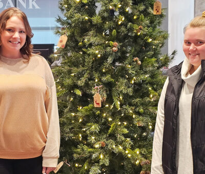 two women posing with christmas tree between them