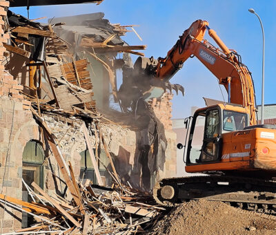 operating crane tearing down historic brick building