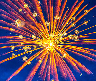 orange and yellow firework explosion against a deep blue sky