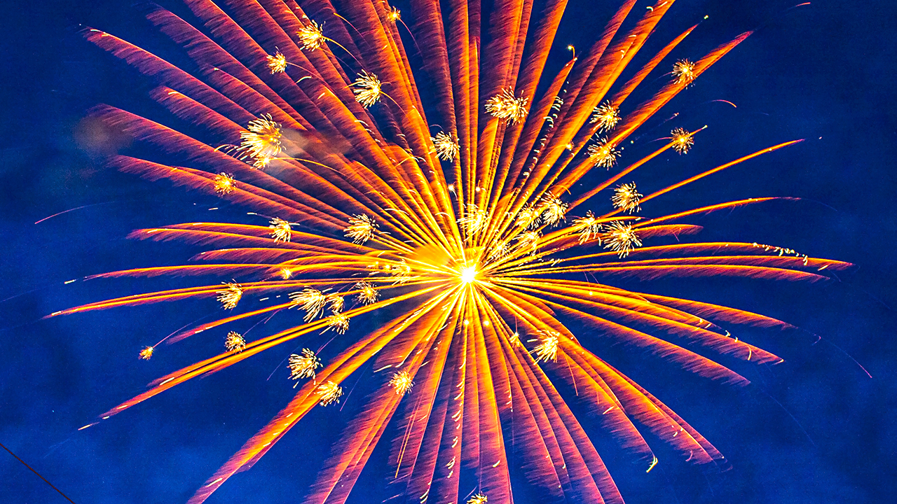 orange and yellow firework explosion against a deep blue sky