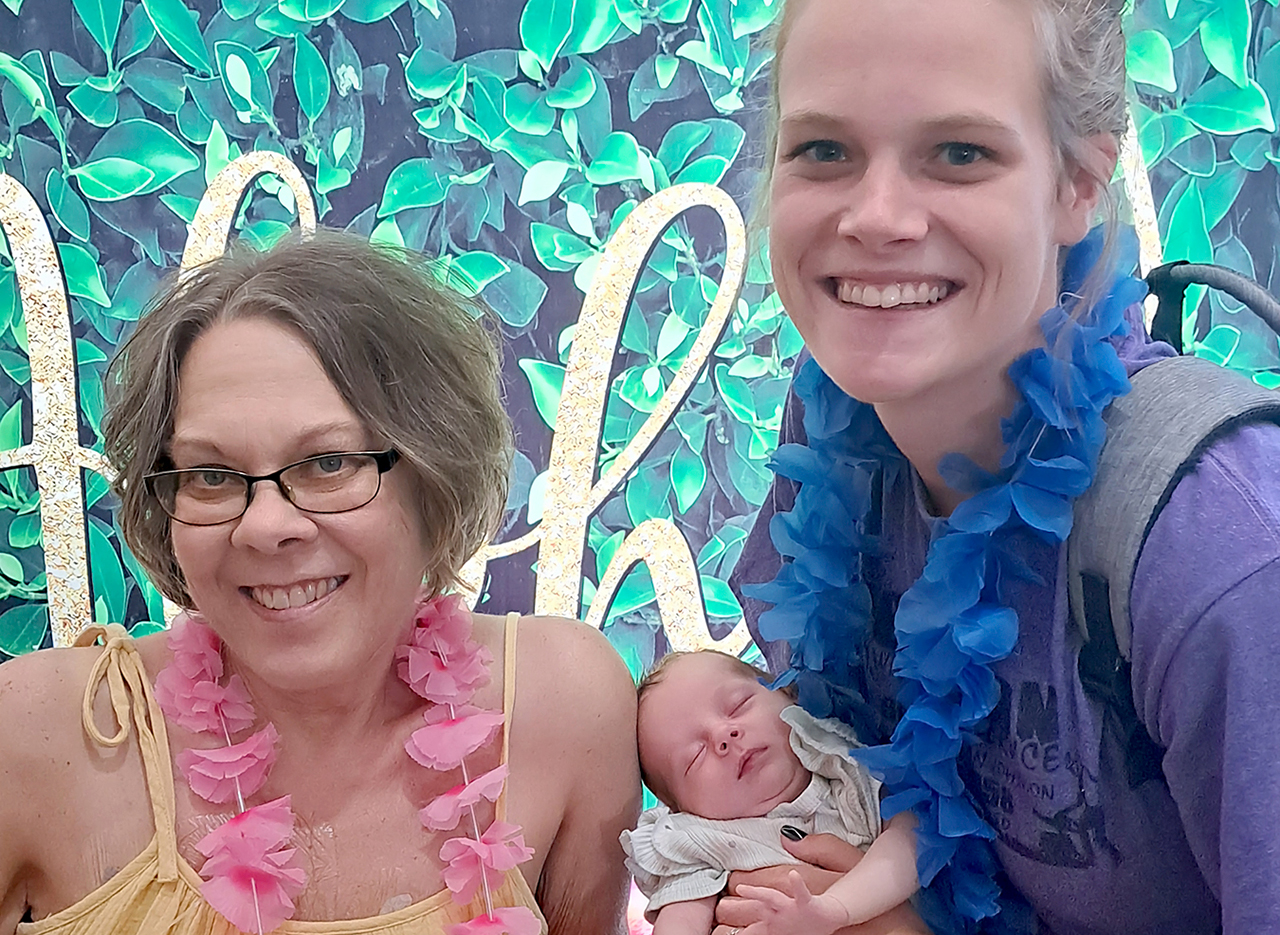 two women posing with a baby