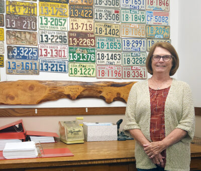 kay mahlen standing in front of wall of license plates