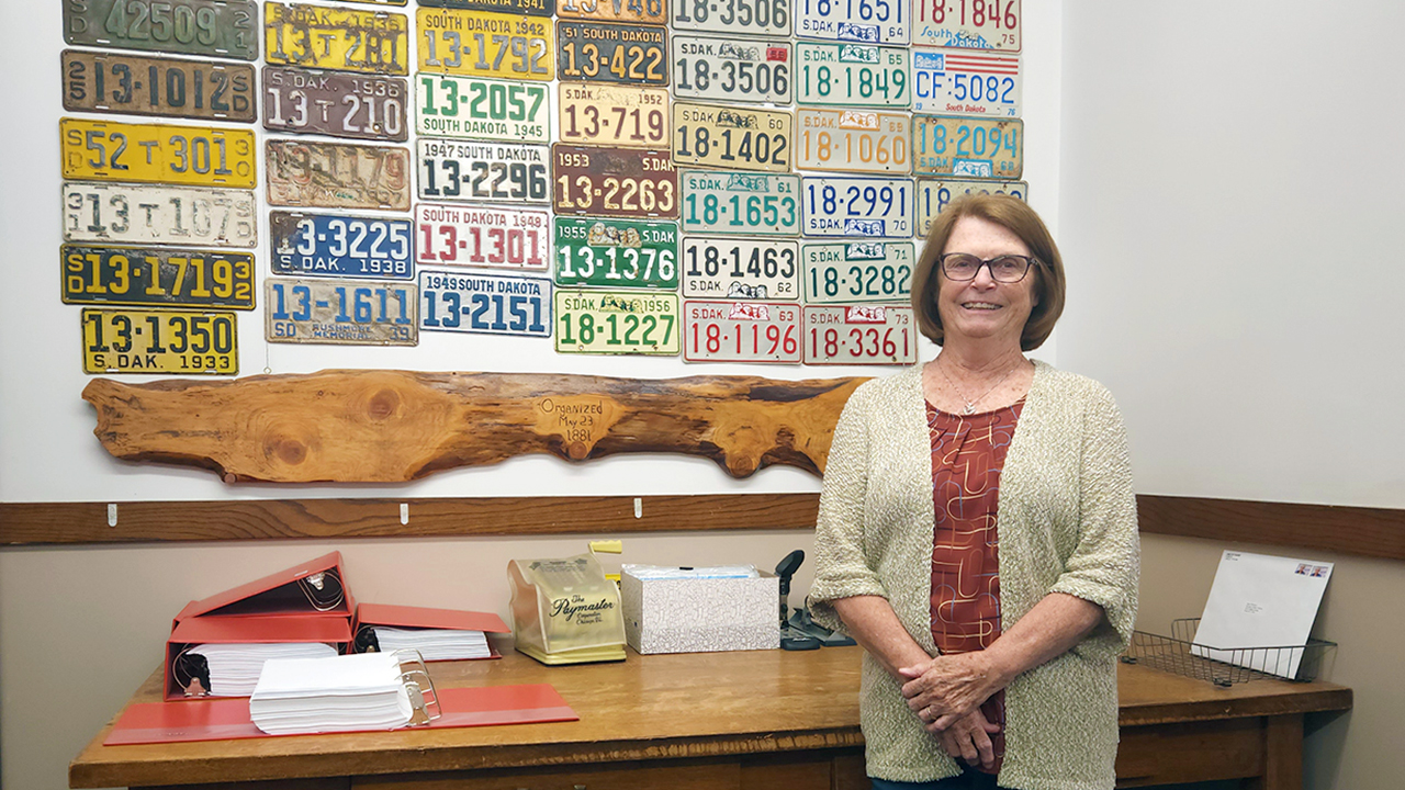 kay mahlen standing in front of wall of license plates