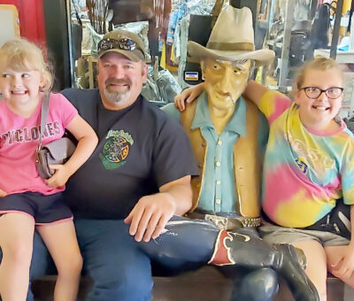 three people posing with cowboy statue