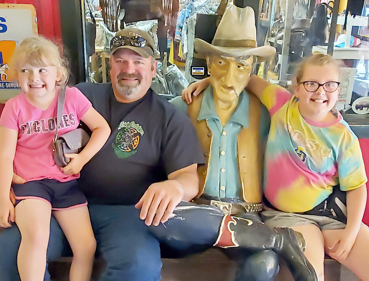 three people posing with cowboy statue