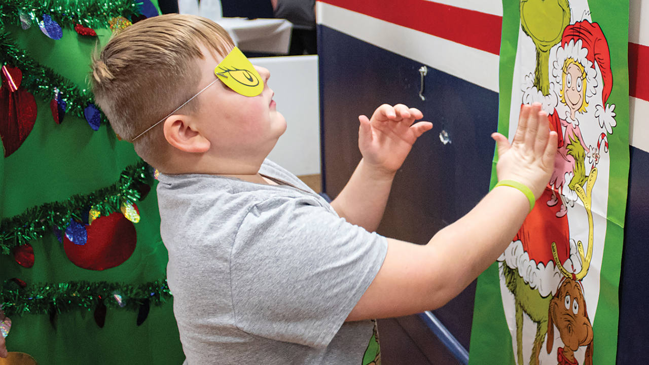 young boy pinning the heart on the grinch