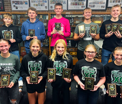 cross country athletes posing with plaques